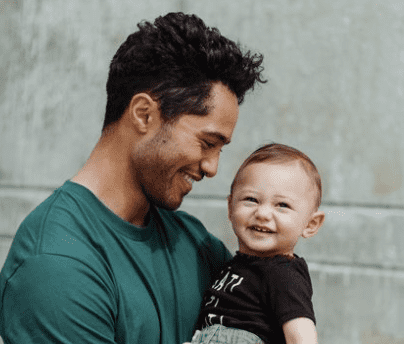 Alex Tarrant looking at his son, Beaumont with love and his son is smiling and looking towards the camera.