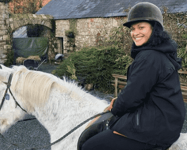 Cynthia Addai-Robinson sitting on the back of the white horse and smiling.
