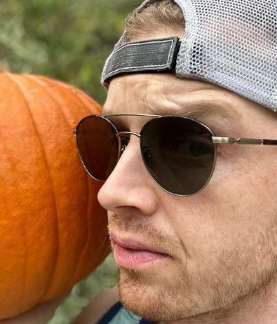 A selfie of Noel Fisher with sunglasses and carrying the pumpkin.