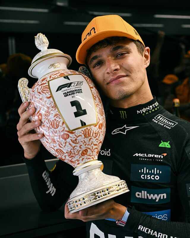 A portrait of Formula 1 driver Lando Norris holding the Hungarian Grand Prix trophy.