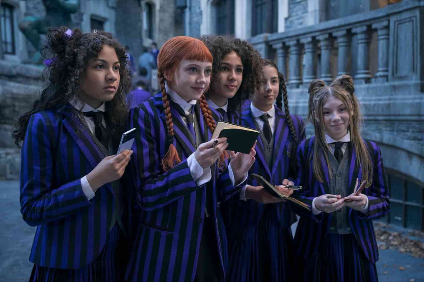 A group of young female students, including Evie Templeton, all wearing matching striped purple and black school uniforms, stand together outdoors.
