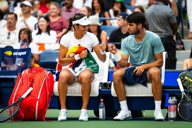 A photo of tennis players Emma Raducanu and Carlos Alcaraz sitting side-by-side on a bench.