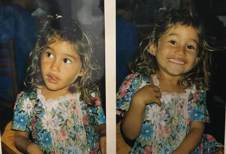 Young girl, Q’orianka Kilcher with curly hair, wearing a floral dress with a white lace collar.