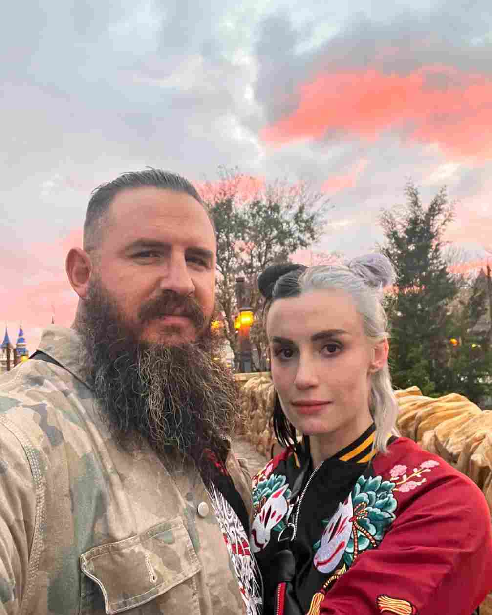 A photo of professional wrestler Brody King and his wife, Julia Hart with a pink-streaked sky in the background.