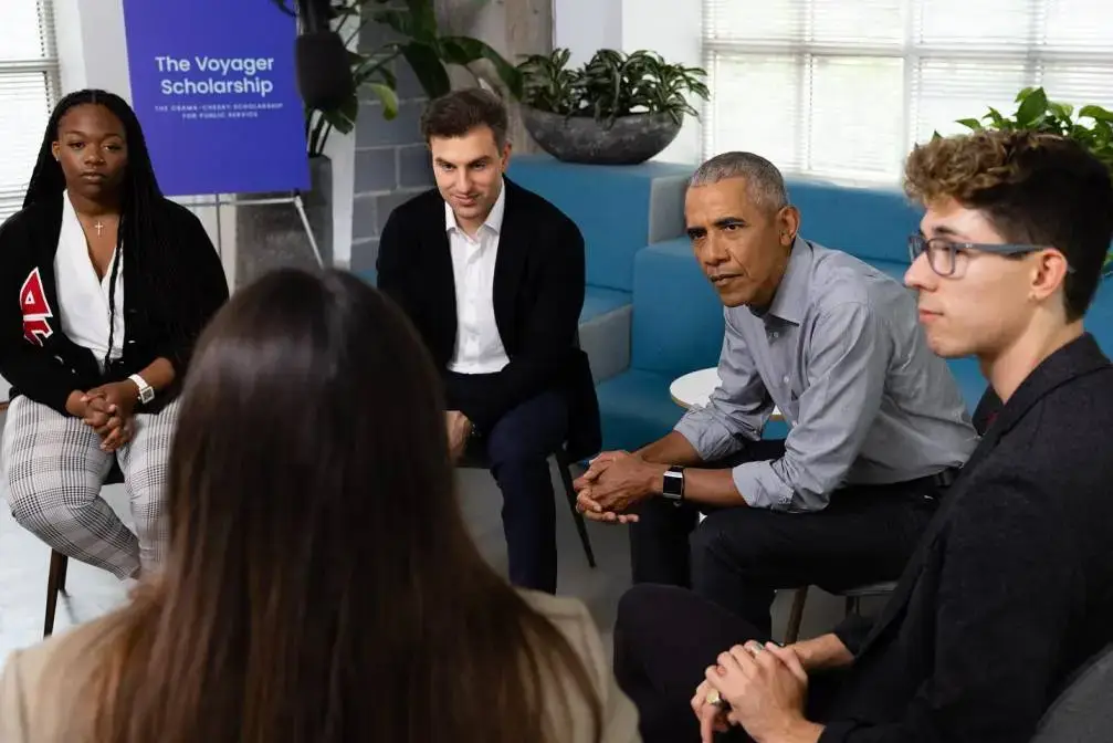 Brian Chesky and Barack Obama participate in a round table discussion with a group of young people.
