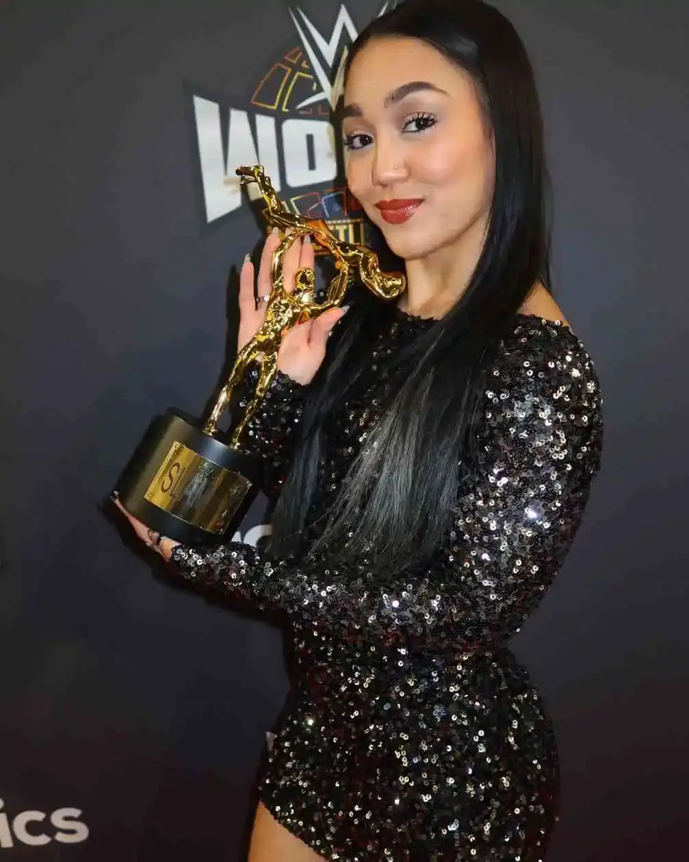 Professional wrestler Roxanne Perez holding a gold trophy.