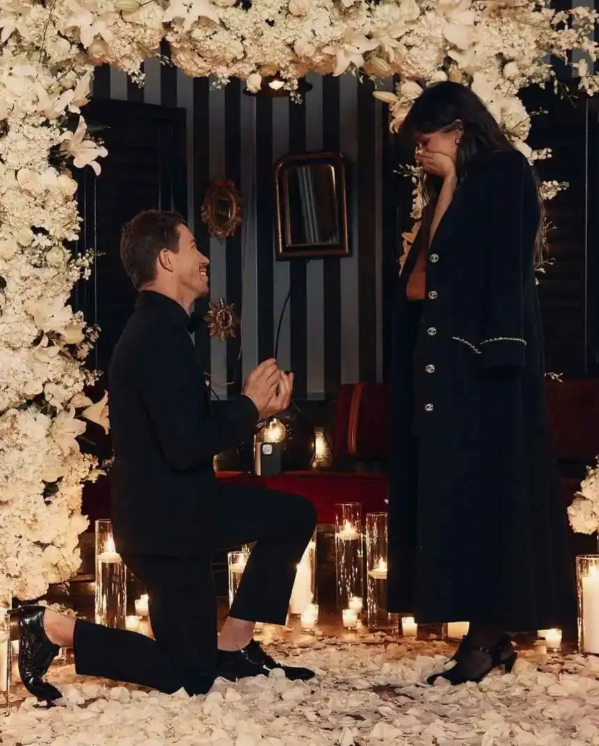 Shaun White proposing on one knee to Nina Dobrev under a floral arch.