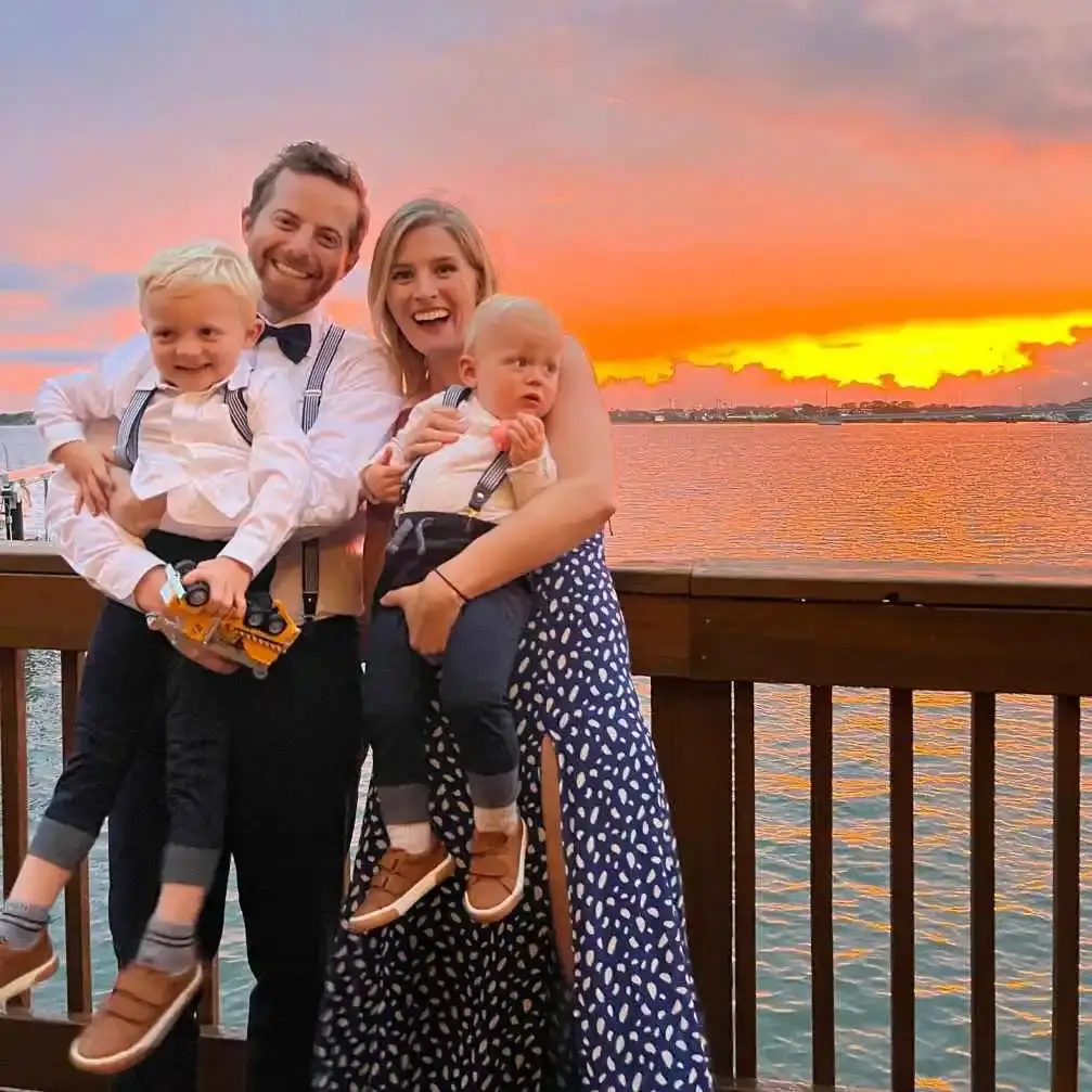 The Fulmer family standing on a deck overlooking the water at sunset.