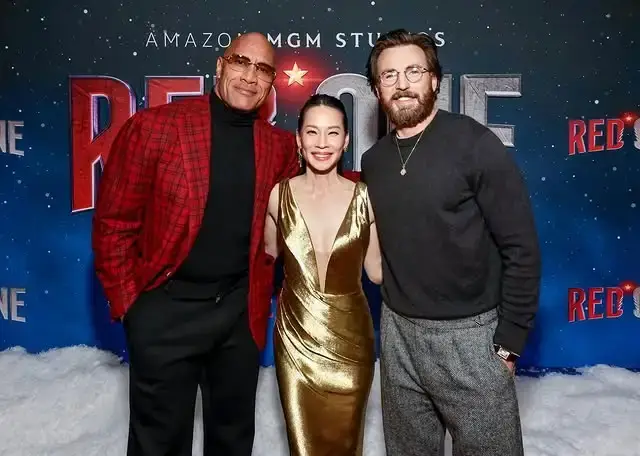 Lucy Liu poses with her co-stars Dwayne Johnson and Chris Evans at a promotional event for their movie.