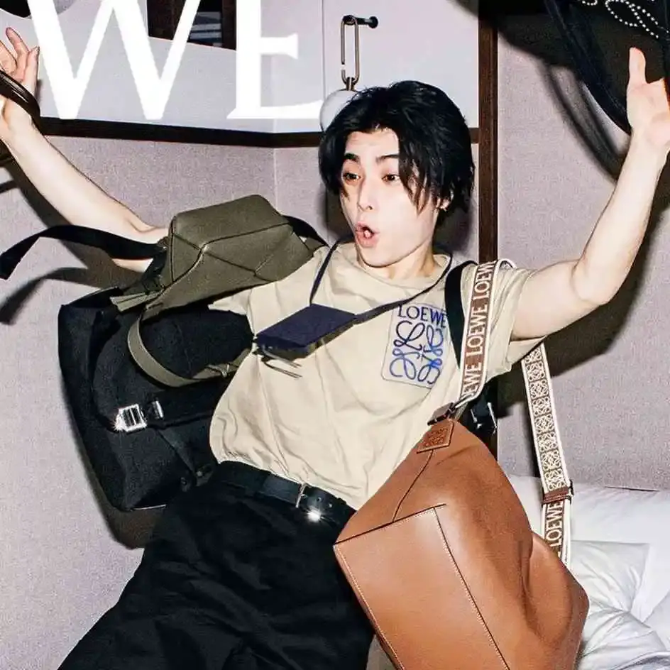 Nijirô Murakami surrounded by various Loewe bags and accessories, with a surprised expression.