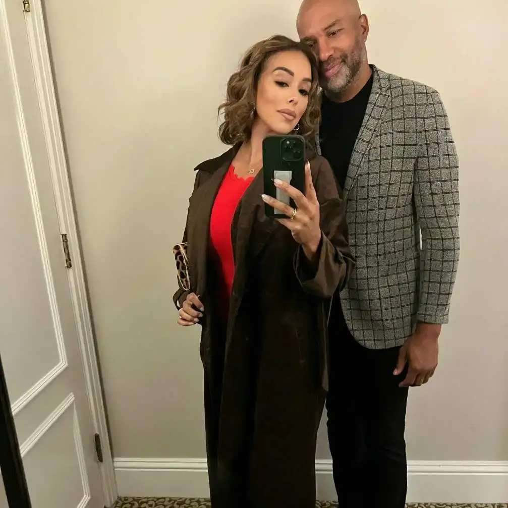 Gloria Govan taking a mirror selfie with her husband, Derek Fisher, who is standing behind her.
