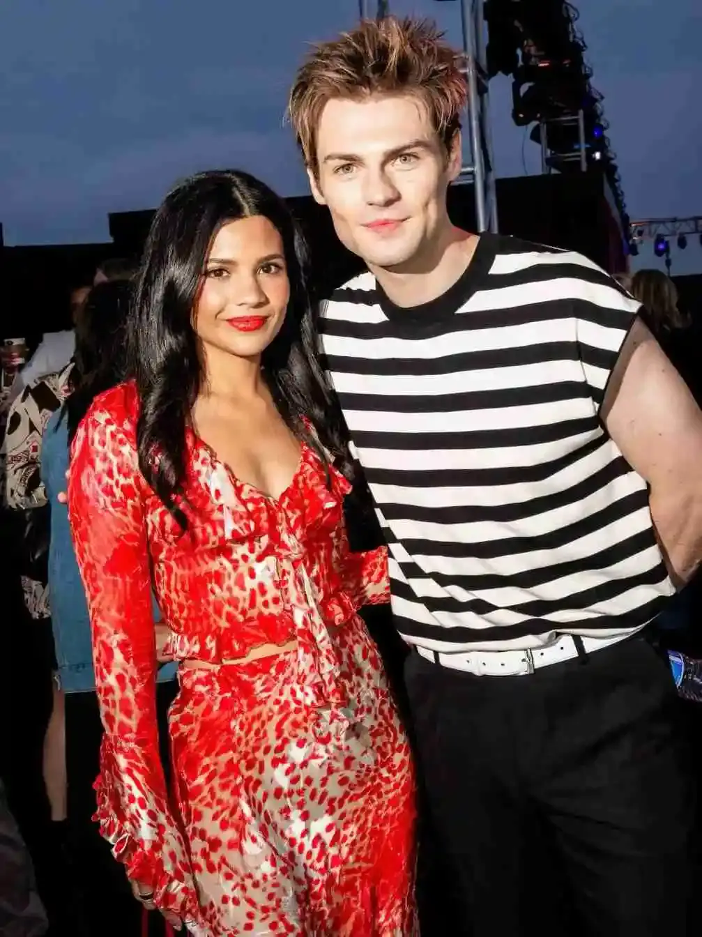 Nikki Rodriguez in a red and white print dress posing with Noah LaLonde in a striped shirt.