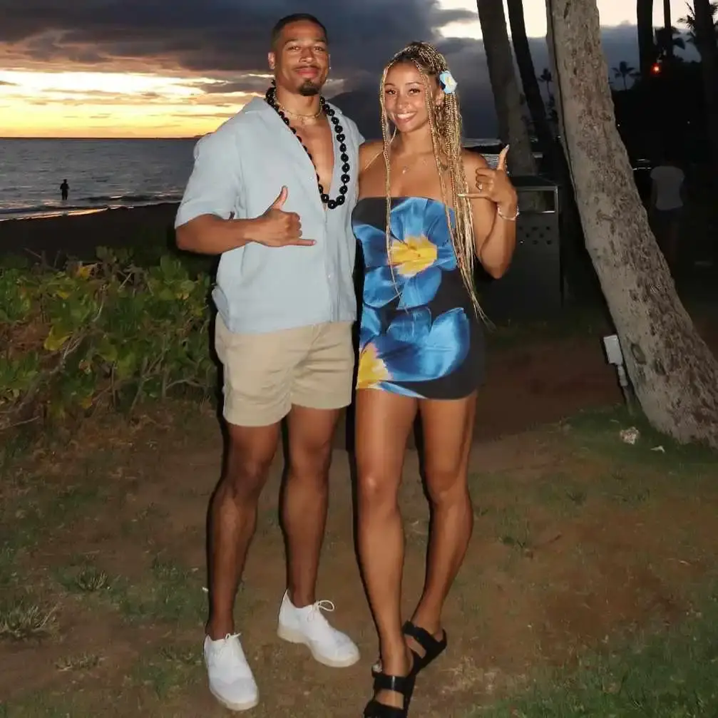 Professional wrestler Carmelo Hayes and his girlfriend, fellow wrestler Kelani Jordan, pose on a beach at sunset.