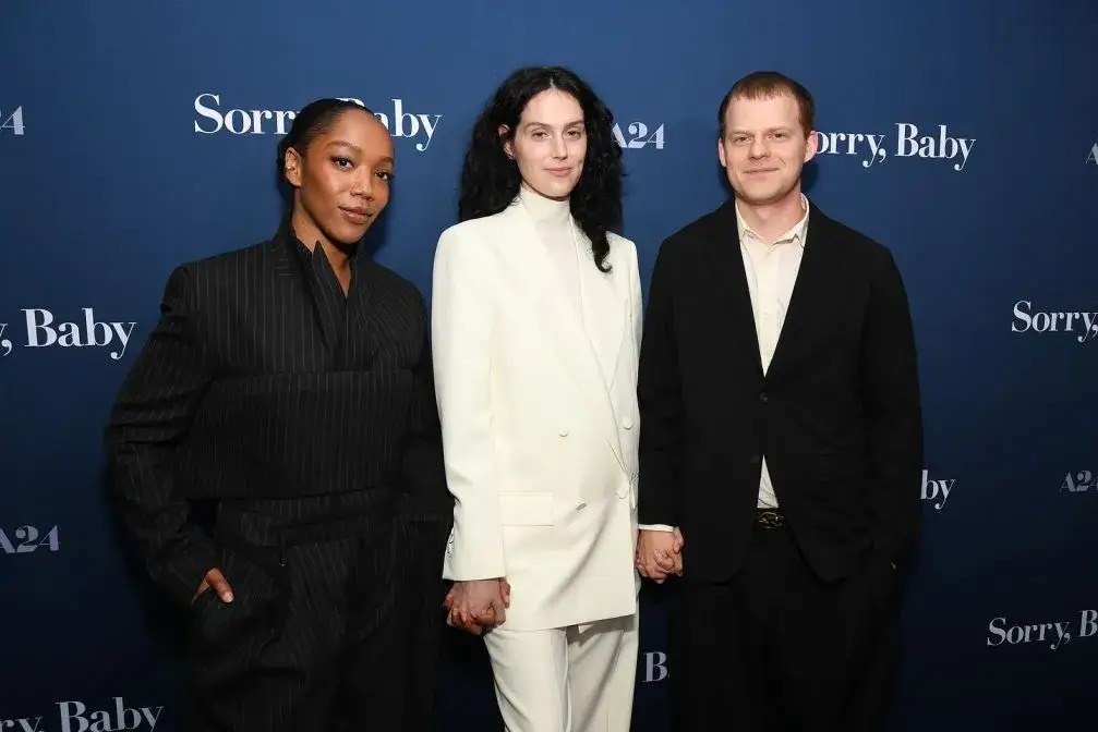 Naomi Ackie, Eva Victor (in white), and Lucas Hedges posing together on the red carpet for the A24 film Sorry, Baby.
