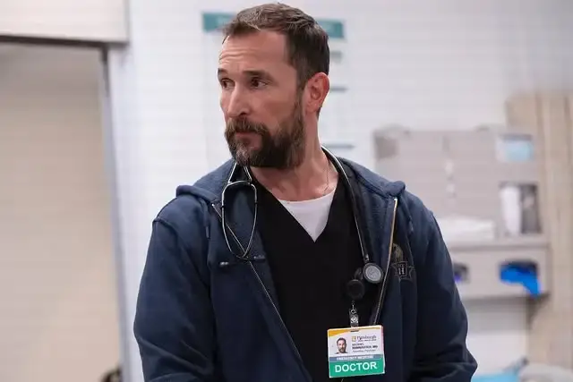Actor Noah Wyle as Dr. Michael Wright wearing scrubs, a hooded jacket, and a stethoscope.