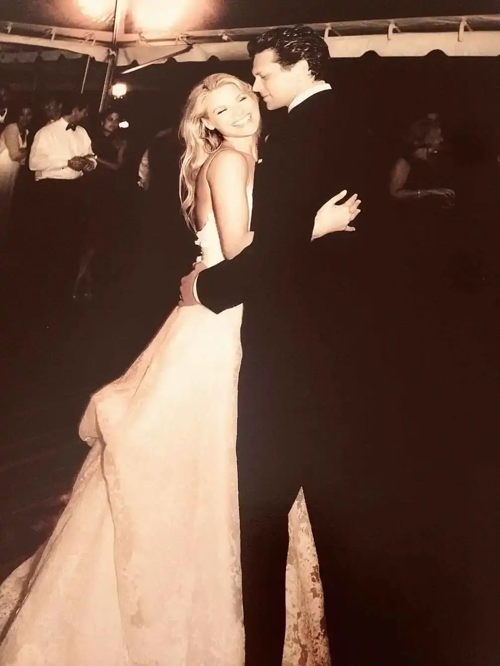 Sepia-toned photo of Ali Larter, in a wedding dress, smiling and dancing closely with her husband, Hayes MacArthur, in a tuxedo.