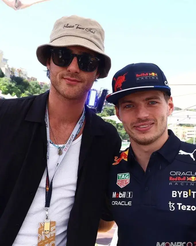 Actor Jacob Elordi in a bucket hat and sunglasses poses for a selfie with Formula 1 driver Max Verstappen, who is wearing a Red Bull Racing team shirt and hat.