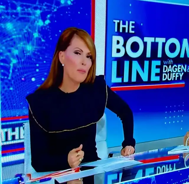 Financial journalist Dagen McDowell is seen on set wearing a dark top with structured, gold-trimmed shoulders while anchoring a Fox Business news segment.