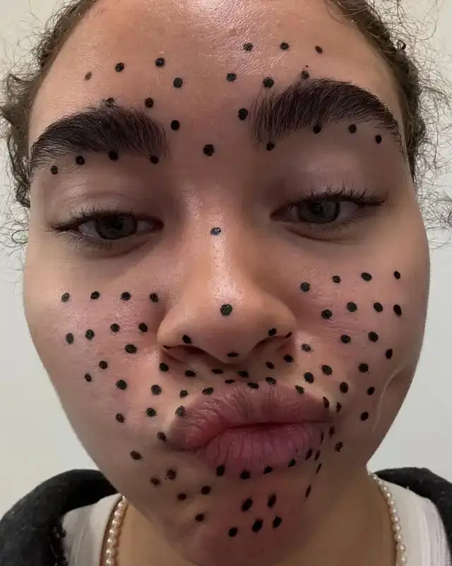Actress Bailey Bass wearing a grey performance capture suit with facial tracking dots and a head-mounted camera rig during a shoot for Avatar: The Way of Water.