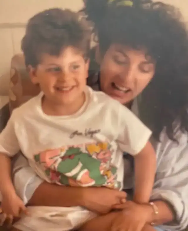 Jonah Hill sits on the lap of his mother, Sharon Feldstein, in a nostalgic, vintage-style childhood photograph.
