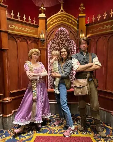 Mandy Moore and her child pose for a photo with Rapunzel and Flynn Rider at a Disney theme park.