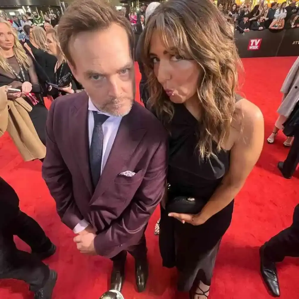Will Forte and his wife, Olivia Modling, look up into a high-angle camera with playful facial expressions while posing on the red carpet at the 2024 Logie Awards.