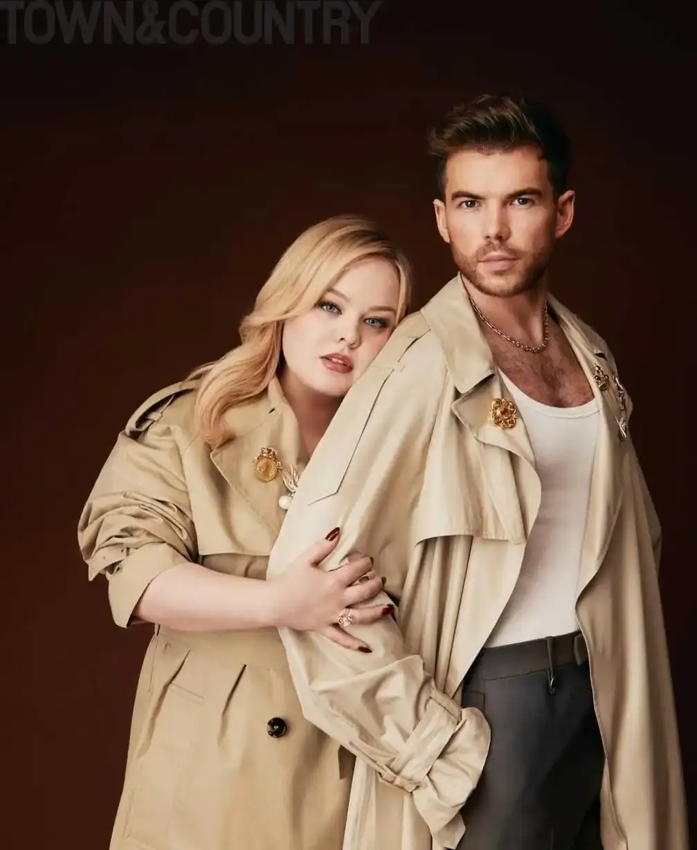 Nicola Coughlan leans her head against Luke Newton’s shoulder while both wear matching tan trench coats for their Town & Country digital cover shoot.