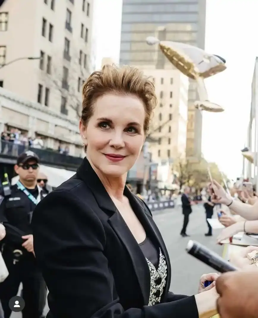 Actress Elizabeth Perkins smiles while interacting with fans and signing autographs on a city street during a public appearance.