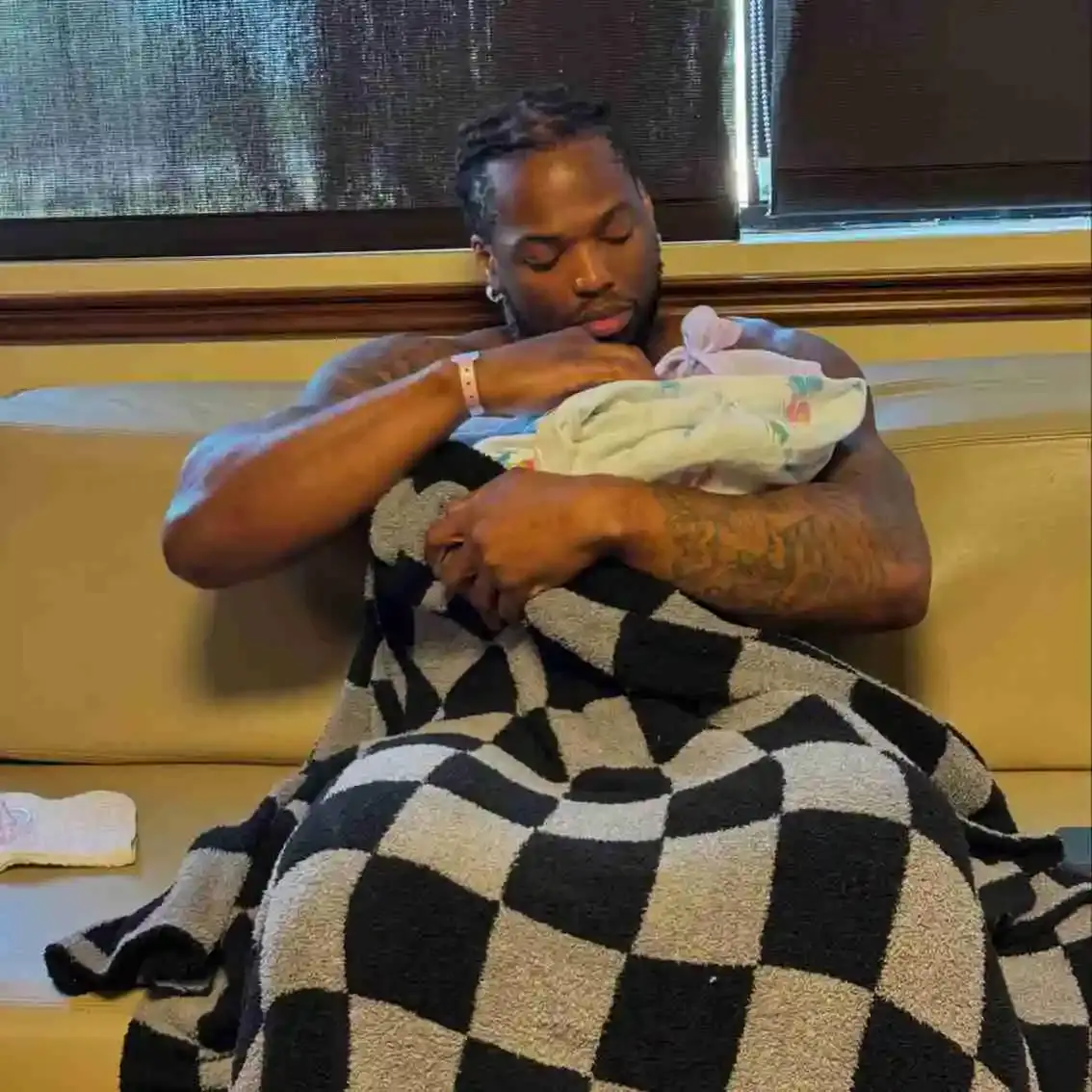 Derrick Henry holds his infant daughter, Celine Amor, while lying in a white floral backdrop decorated .