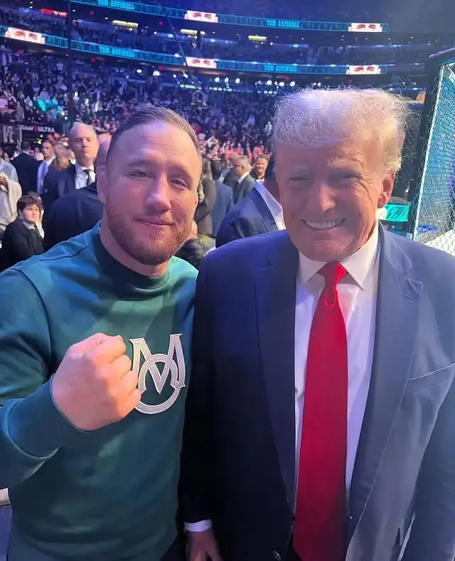 Justin Gaethje stands next to Donald Trump at a public event, both looking toward the camera and smiling in a well-lit indoor setting.