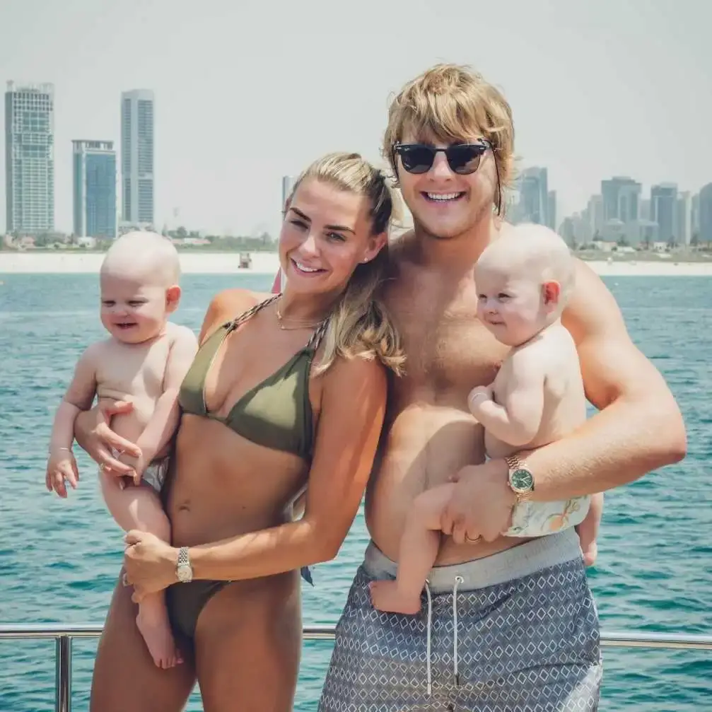 Paddy Pimblett and his wife Laura smile on a boat while each holding one of their twin daughters, Betsy and Margot.