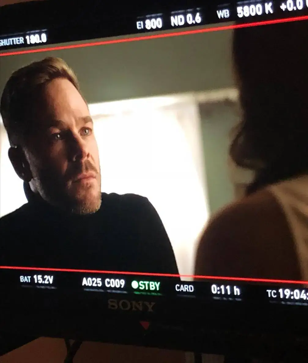 Shawn Ashmore, known for his roles in The Rookie, is captured in a serious moment on set through a production monitor.