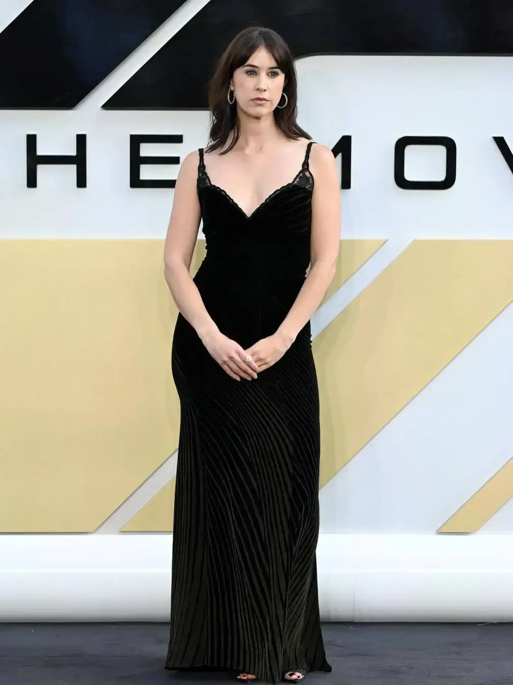 Liz Kingsman poses on the red carpet at the European Premiere of F1: The Movie at Cineworld Leicester Square, wearing a sheer black dress with white floral details and a matching blazer.