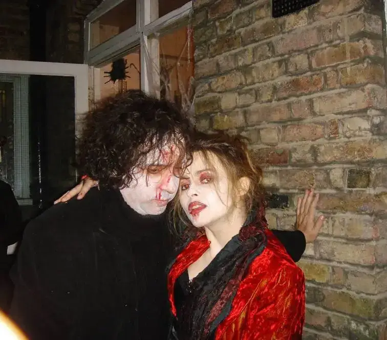 Tim Burton and Helena Bonham Carter pose together in gothic Halloween costumes with pale face makeup and faux blood.