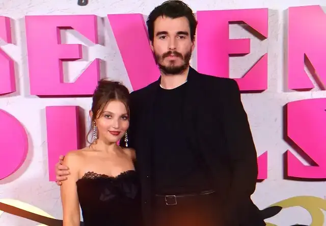 Mia McKenna-Bruce and Corey Mylchreest stand together on the red carpet at the Seven Dials UK Premiere in London, both wearing elegant black evening attire.