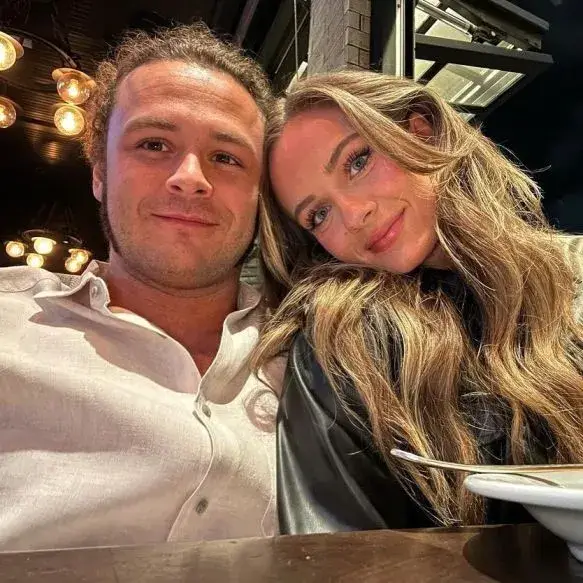 Anna Jay and Jack Perry lean their heads together while smiling for a close-up selfie at a restaurant table.