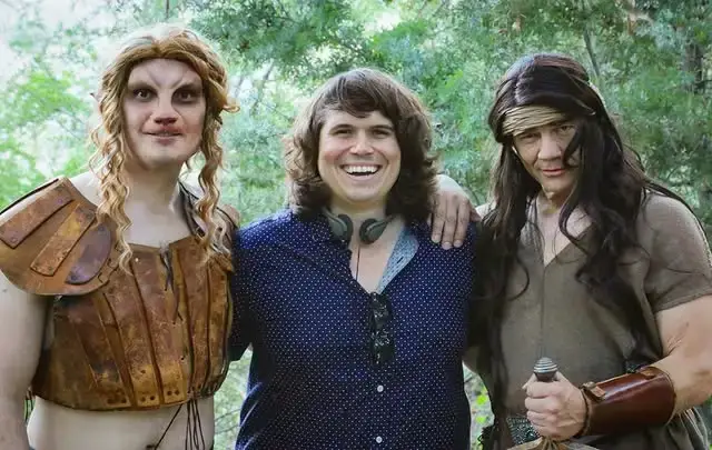 Steve Greene and Matthew Glave pose in fantasy costumes alongside director Michael Gallagher in a wooded outdoor setting.