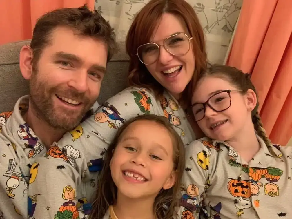 Actress Sara Rue and her husband Kevin Price smile warmly while posing outdoors with their two young daughters, Talulah Rue and Adelaide Rue.