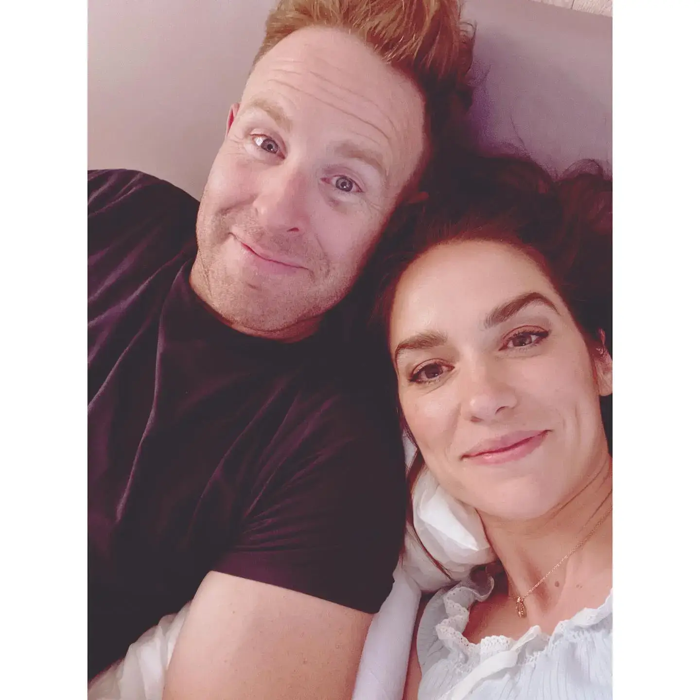 A close-up selfie of Jeff Pentecost and Melanie Scrofano smiling together while lying down.