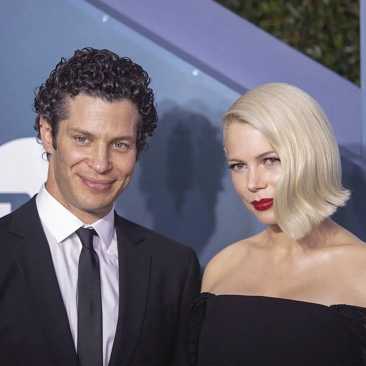 Thomas Kail and Michelle Williams pose together in formal black attire at a red carpet event.