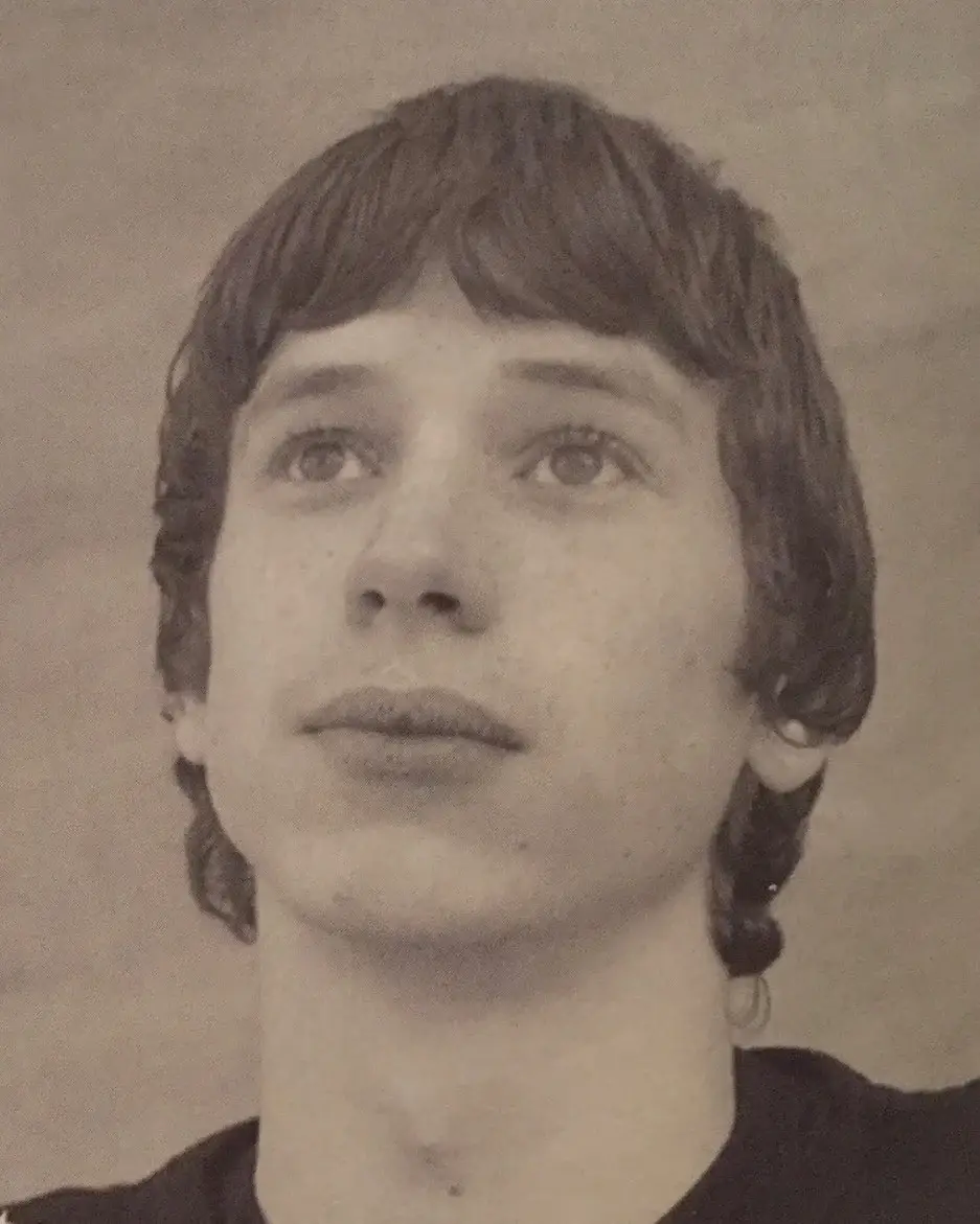 A vintage black and white headshot of a young Herbert Nordrum looking upwards with a soft expression and shaggy hair.