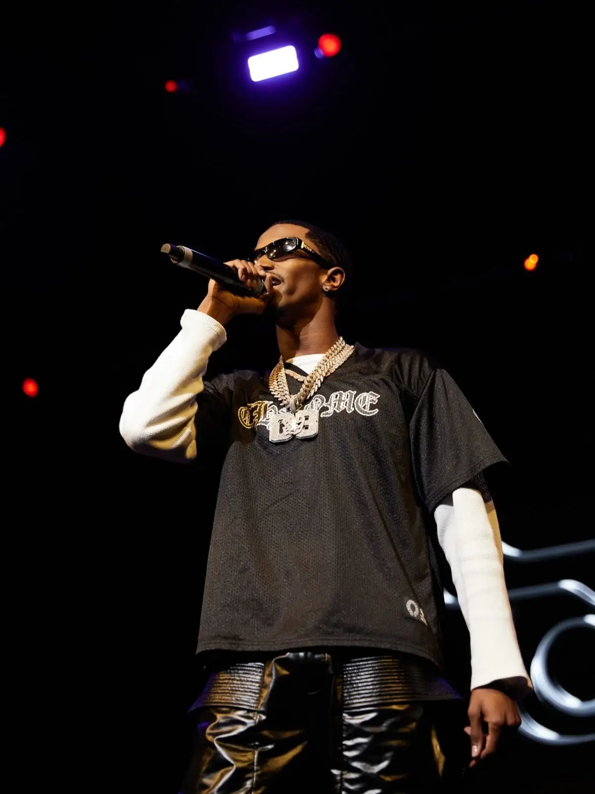 Christian Combs performing on stage in a black Chrome Hearts jersey, iced-out chains, and sunglasses.