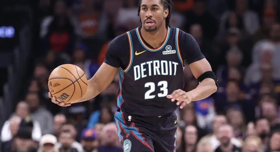 Jadan Levy dribbles a basketball while wearing a black and teal Detroit Pistons jersey with the number 23.