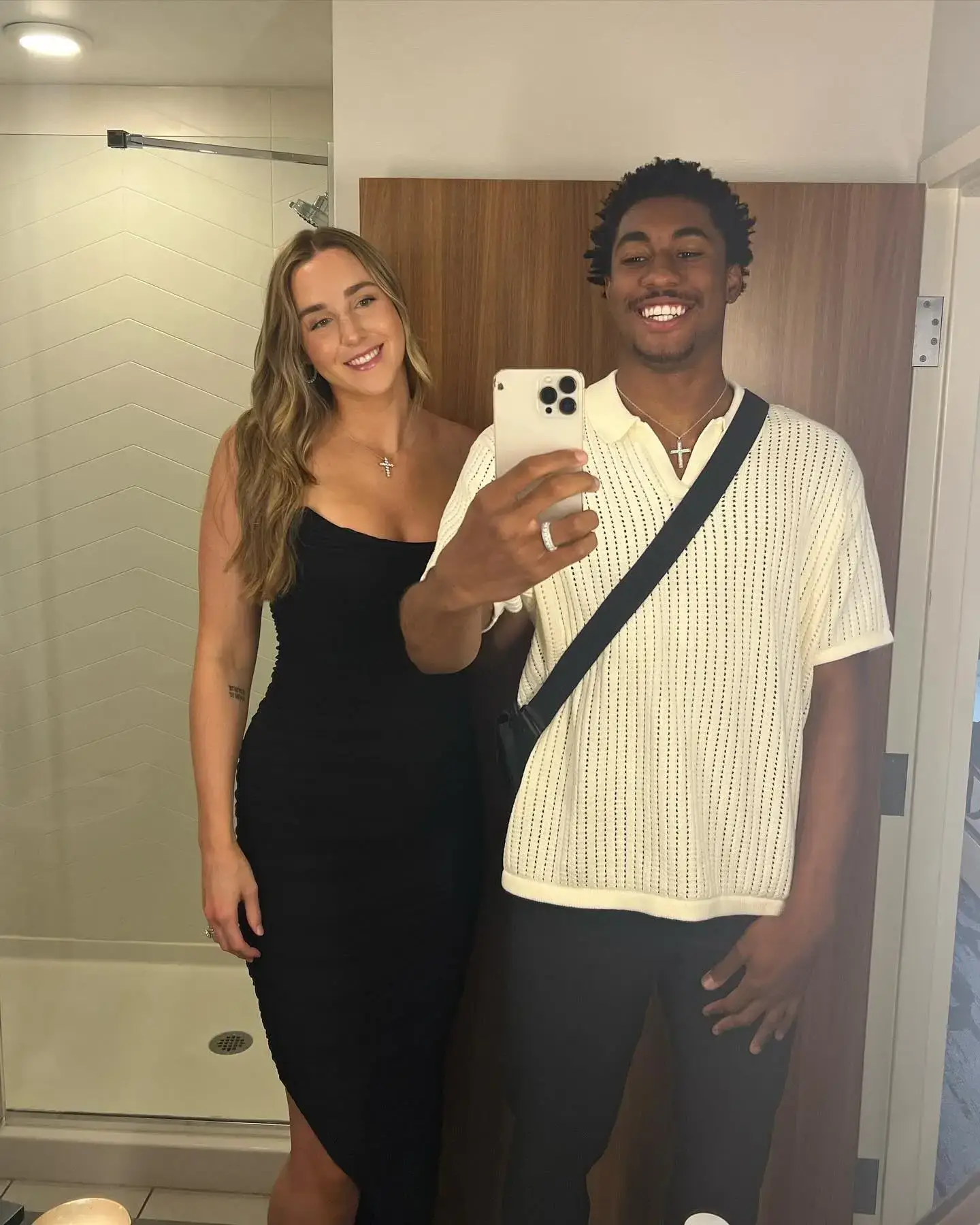 Caitlyn Levy smiles next to Jaden Ivey as they take a mirror selfie together in a bathroom.
