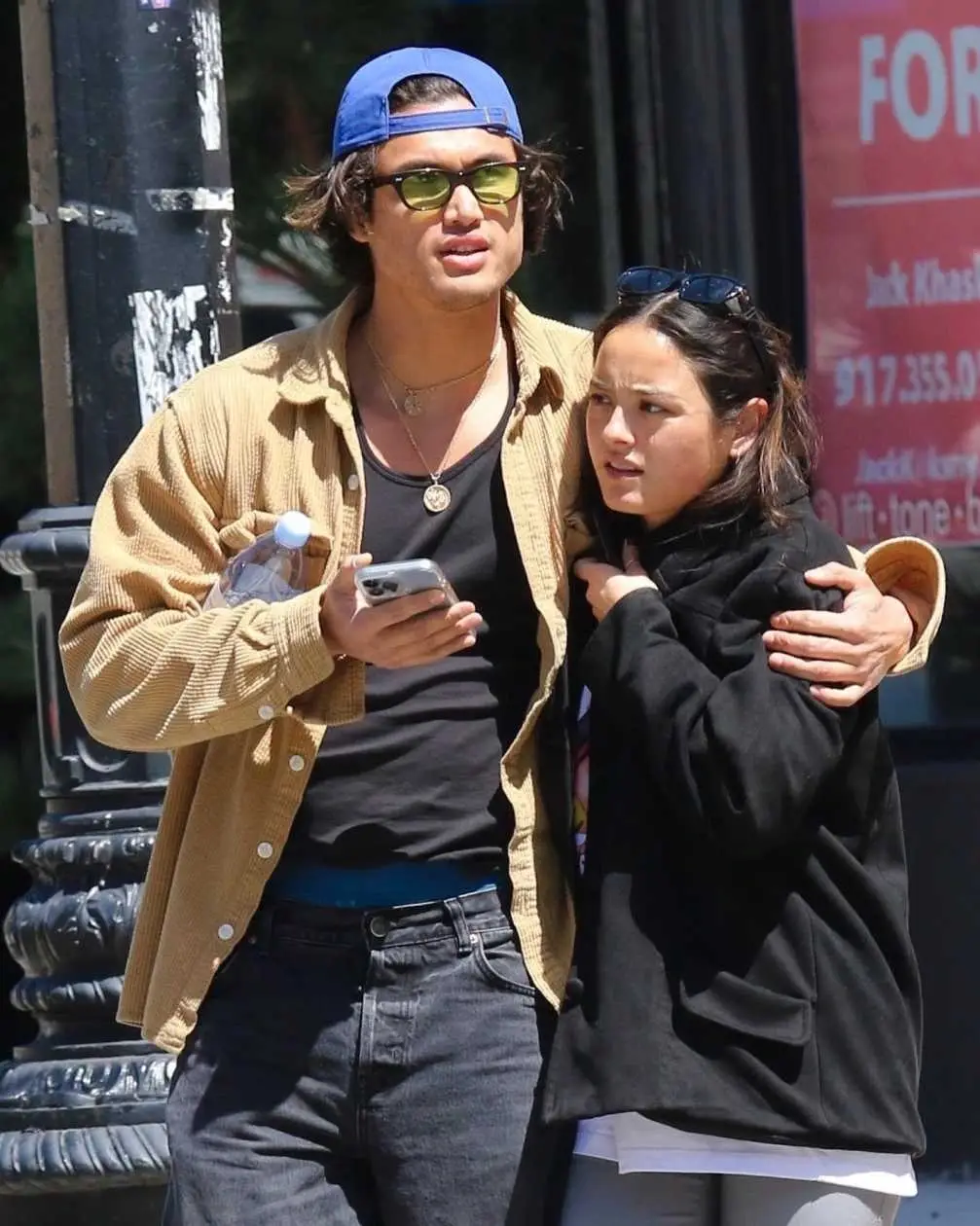 Charles Melton walks with his arm around Chase Sui Wonders on a sunny city street.