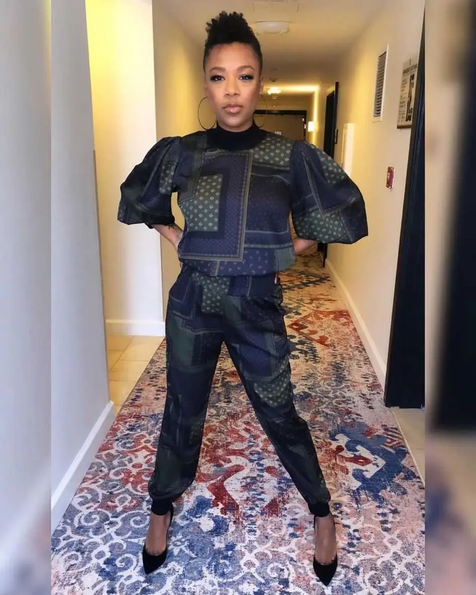 Samira Wiley posing in a hallway wearing a dark patterned two-piece outfit.