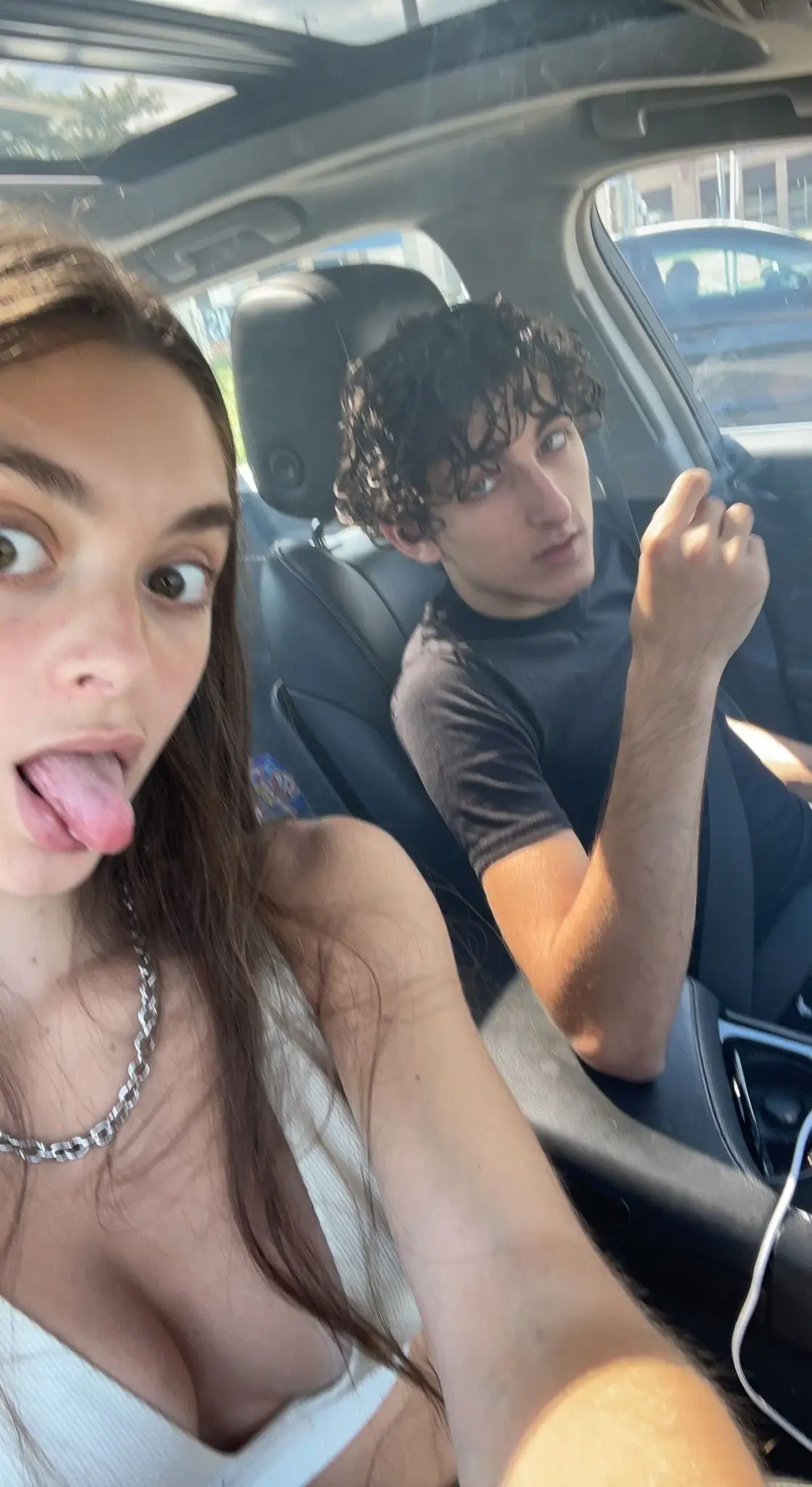 Mackenzie Shirilla sticks her tongue out while taking a car selfie next to Dominic Russo, who sits in the driver
