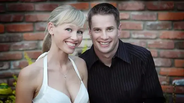 Sherri Papini, wearing a white halter top, smiles alongside her former husband, Keith Papini, who wears a black striped shirt in front of a brick wall backdrop.