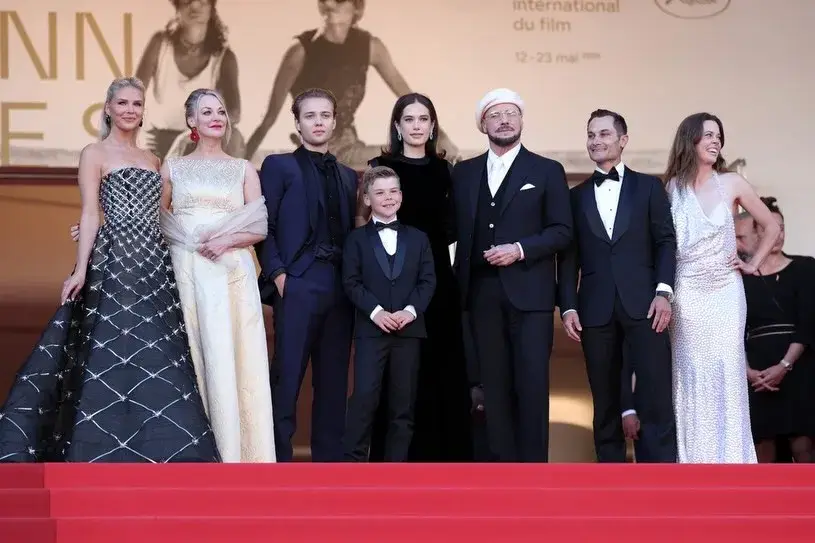 John Travolta stands with his family and guests on the red carpet stairs at the Cannes Film Festival.