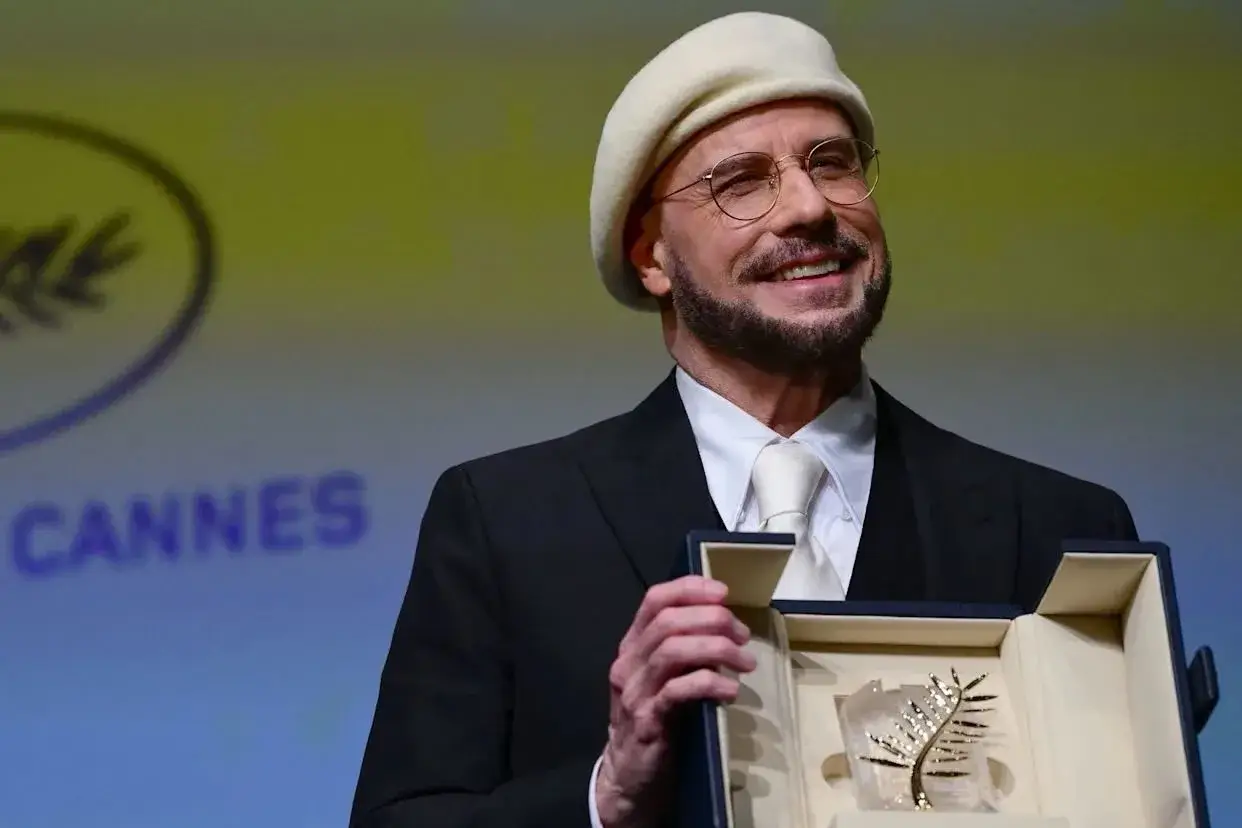 John Travolta smiles while holding his open honorary Palme d
